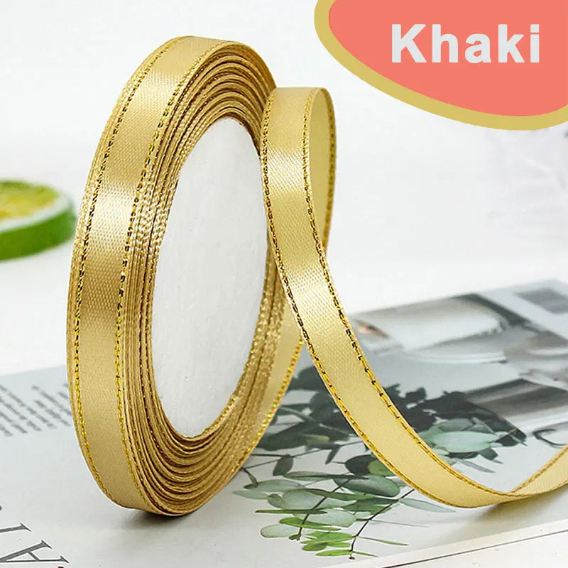 Roll of gold edge satin ribbon with a white center visible on a surface.