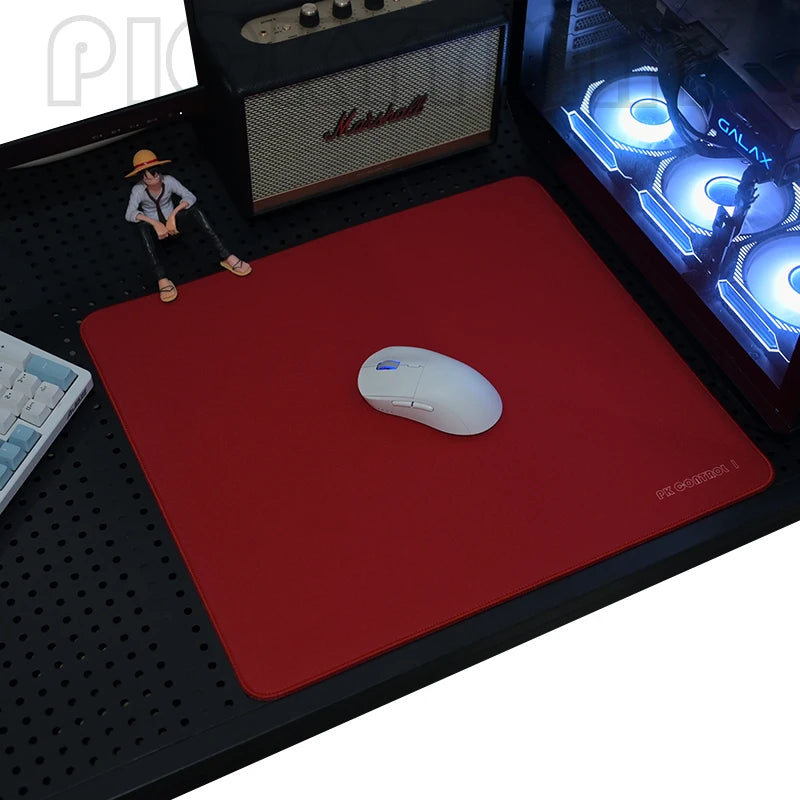 A red gaming mouse pad with a white wireless mouse and a miniature figure on a black desk mat.