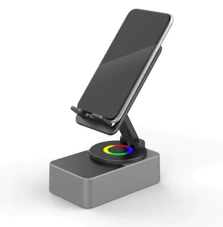 A wireless speaker with an adjustable phone stand and night light resting on a gray base.