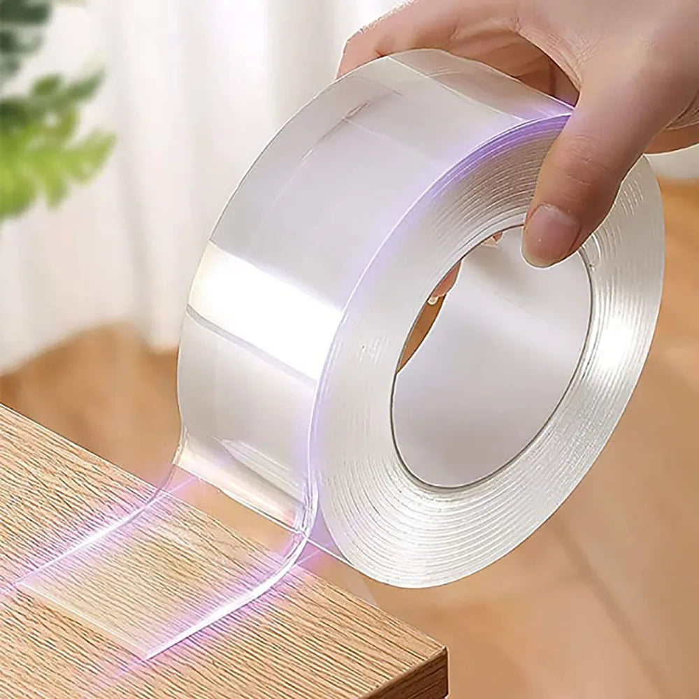 A hand is applying a roll of clear adhesive tape to a wooden surface, showing the tape being dispensed.