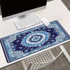 A blue and white vintage Persian rug design gaming mouse pad with a non-slip rubber base on a white desk.