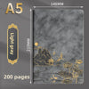 A luxury gray notebook with gold foil illustrations of mountains, pagodas, and flowers.