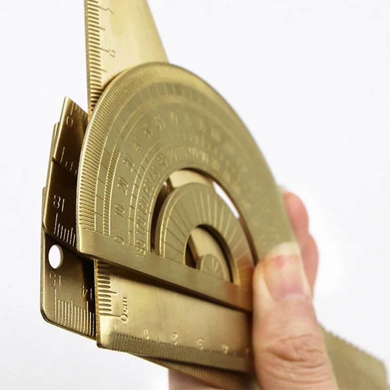 A hand holds a brass drafting set with precision measuring tools and a graduated circle.