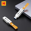 A silver Kodak metal USB flash drive with a leather orange lanyard is shown next to a laptop.