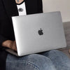 Una persona sostiene una MacBook plateada con una funda protectora sobre su regazo.