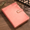 A pink A5 retro leather notebook lying on a wooden surface.