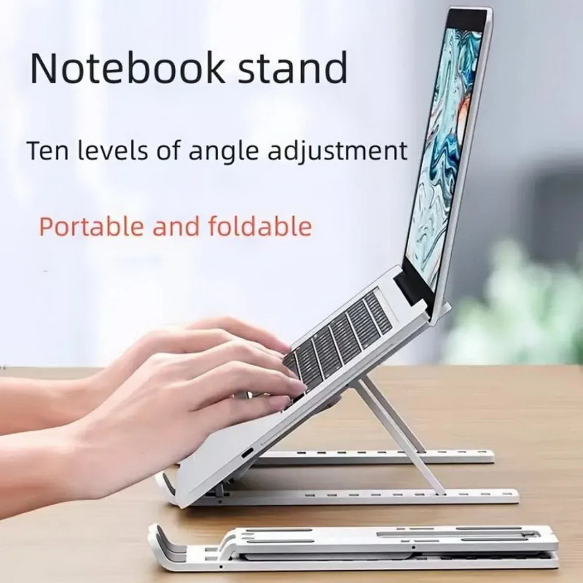 A portable and foldable laptop stand is shown with a hand adjusting the angle of a silver laptop.