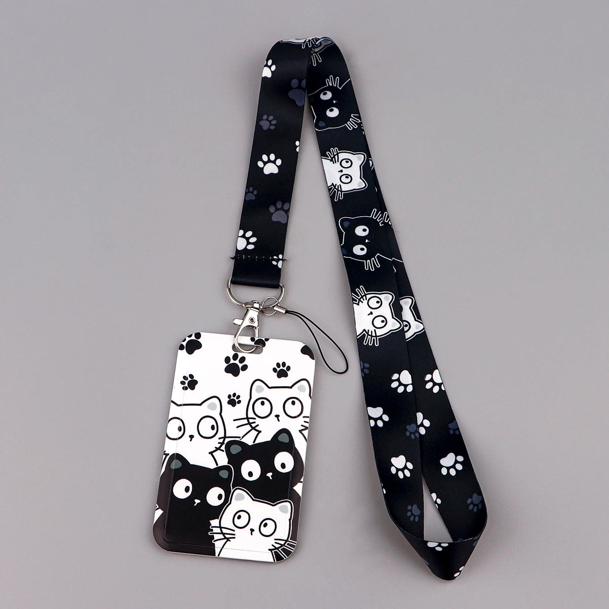 A black and white cartoon cat card holder lanyard with a patterned strap and clear plastic card holder.
