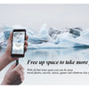 A hand holds a black smartphone displaying a screen, with icebergs and water in the background.