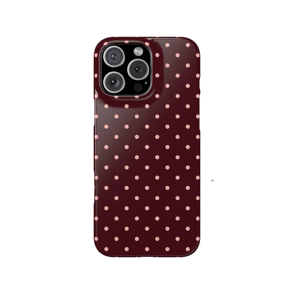 A dark maroon phone case with a pattern of small, light pink polka dots.