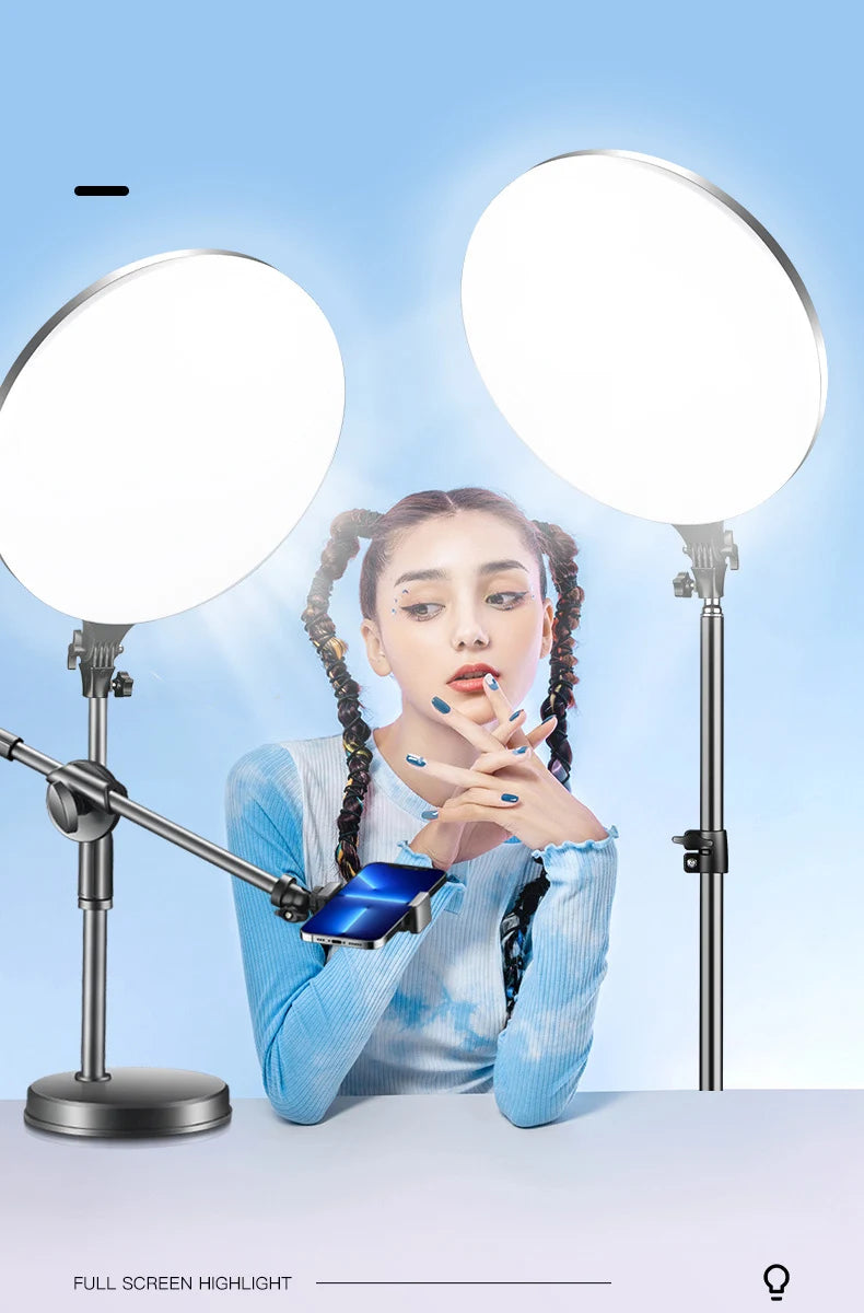A woman holds up a blue smartphone in front of two bright LED ring lights mounted on tripods.