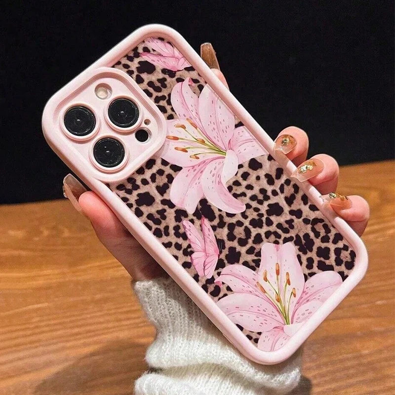 A hand holds a pink leopard print phone case featuring a large pink lily floral design.