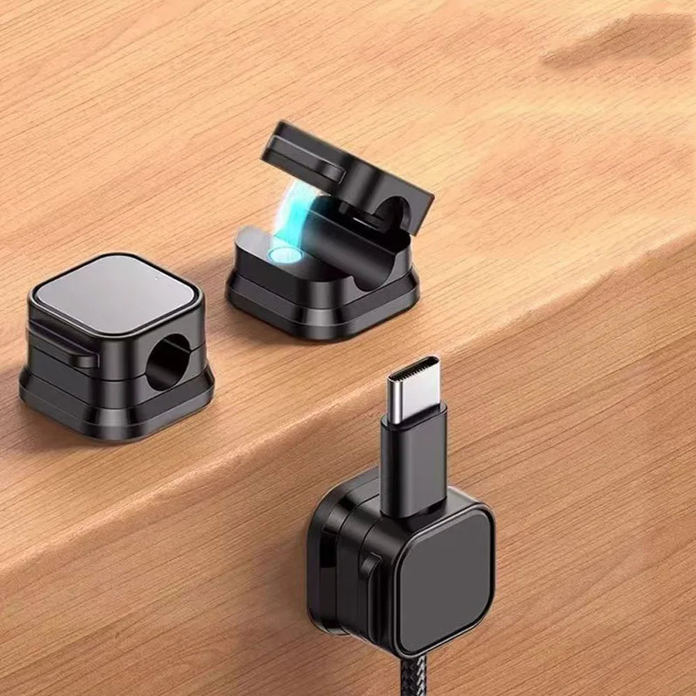 A set of magnetic cable clips, including a clip with a USB-C connector and a black cable, resting on a wooden surface.