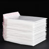 A stack of white self-sealing pearl film bubble shipping bags is shown on a dark surface.