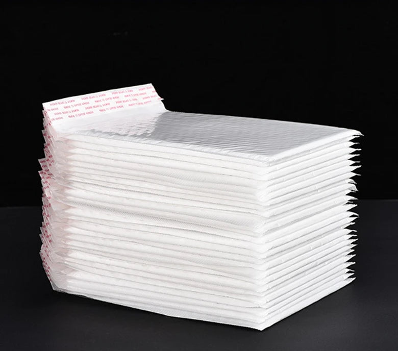 A stack of white self-sealing pearl film bubble shipping bags is shown on a dark surface.