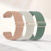 Three colored adjustable elastic sports bands in pink, beige, and green laid out on a white marble surface.