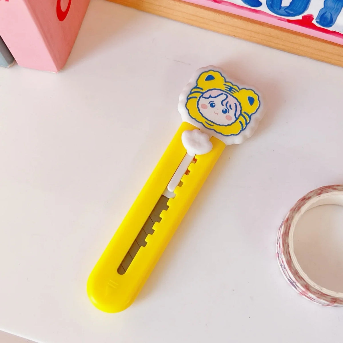 A yellow mini cat paw cutter with a round head and white fluff, used for mail and crafts.