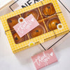 A yellow gift box filled with baked goods and thank you cards for business appreciation