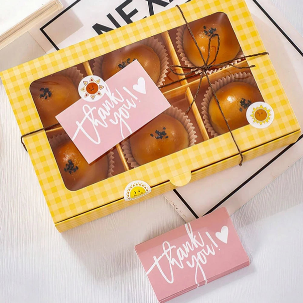 A yellow gift box filled with baked goods and thank you cards for business appreciation