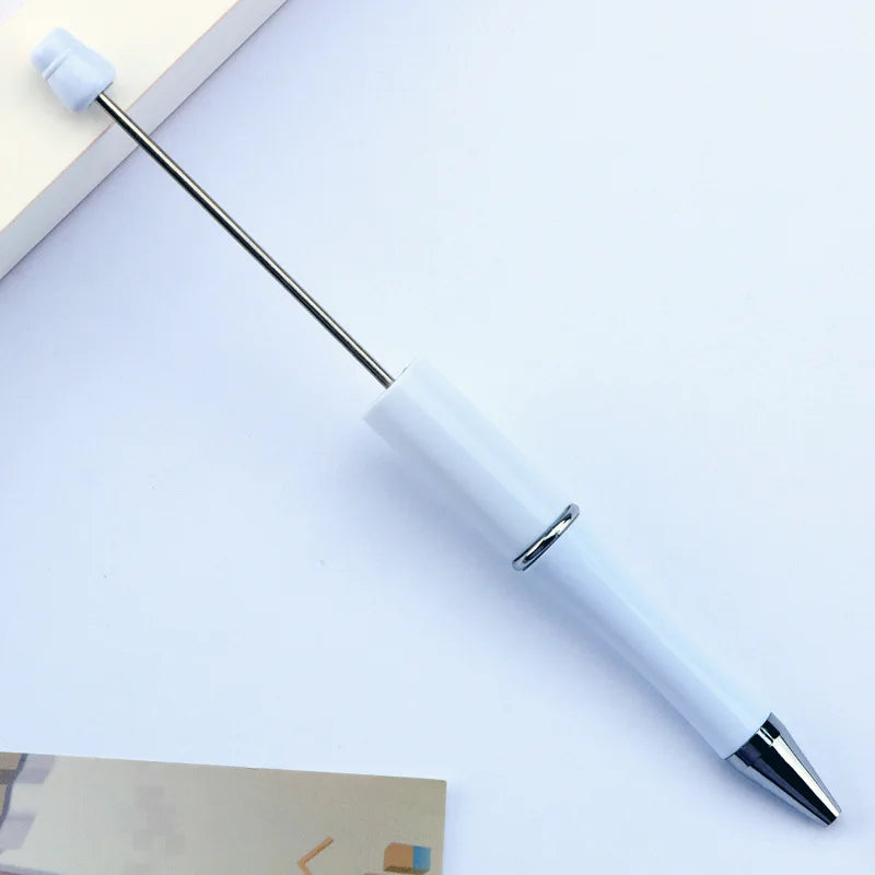A white DIY beadable pen with a silver clip and black ink tip resting on a light surface.