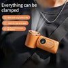 A person is holding a portable clip-on handheld cooling fan with an orange casing and a silver chain.