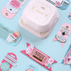 A pink crafting tool with a clear plastic lid and various shaped tags for craft projects