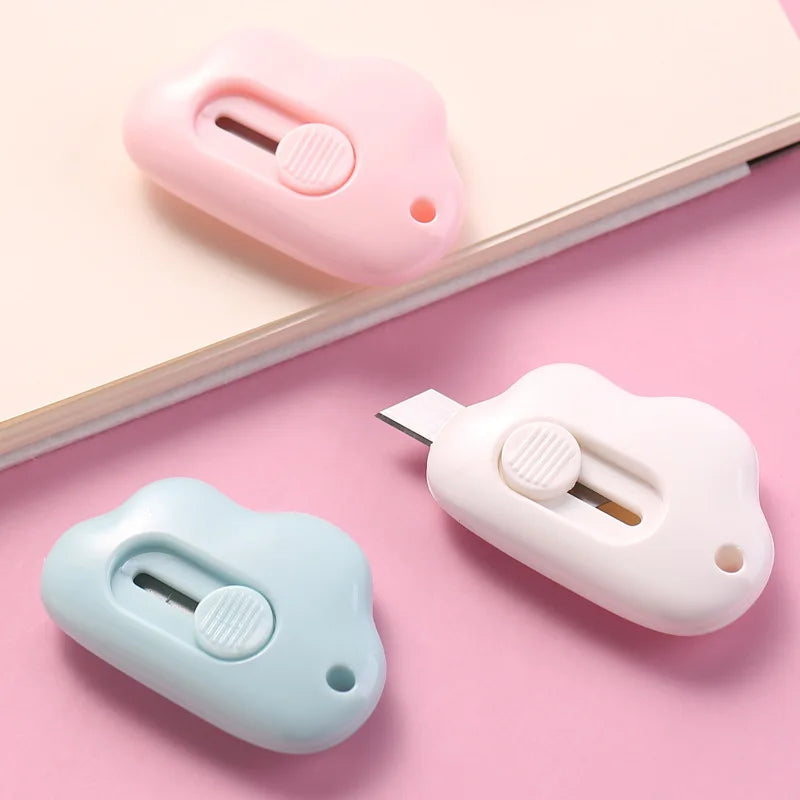 Two portable utility knives in pink and light blue are shown resting on a pink surface.