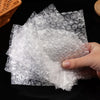 A hand is holding a sheet of transparent bubble wrap padded shipping bags.