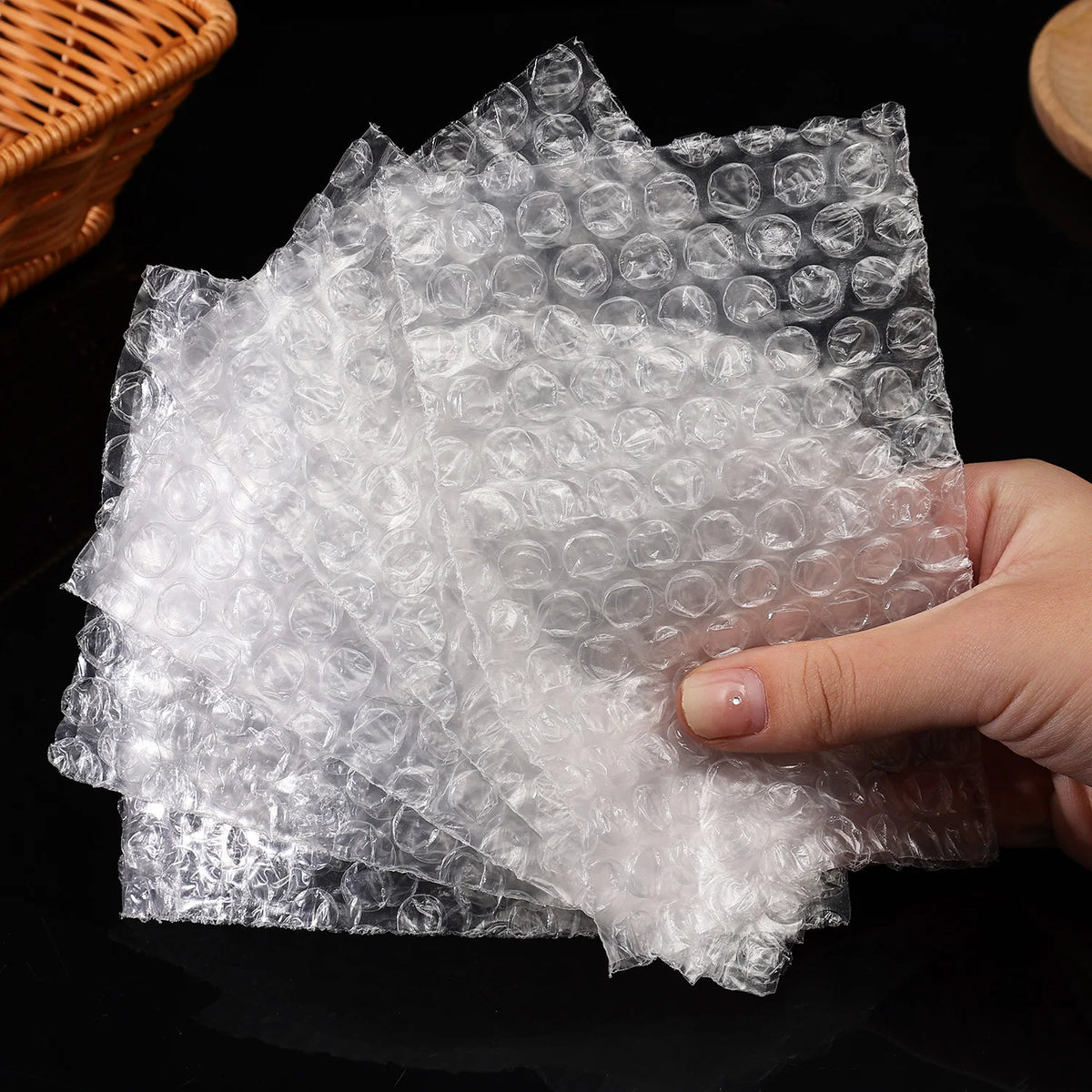 A hand is holding a sheet of transparent bubble wrap padded shipping bags.