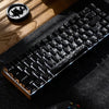A close-up shot of a backlit mechanical keyboard with carbon fiber keycaps resting on a dark fabric surface.