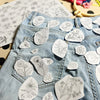 Light wash denim jeans decorated with white embroidery patches featuring floral patterns.