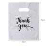 A white thank you gift bag with black script writing on it, showing its dimensions.
