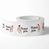 A roll of thank you stickers featuring a hand making a heart gesture on a white background.