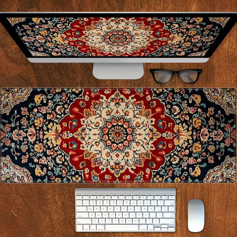 A vintage Persian rug gaming mouse pad with a non-slip rubber base placed on a wooden desk next to a computer monitor and key