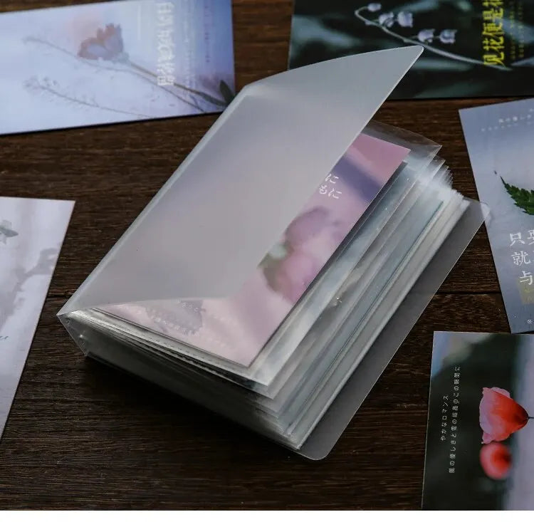 A stack of translucent photo storage booklets with pink and white designs resting on a dark wooden surface.