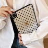 A hand holds a black polka dot protective case for an iPad Pro against a white shirt.
