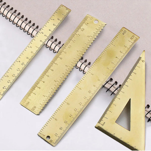 Ein Set Messing-Zeichenwerkzeuge, einschließlich Lineale und Dreieck für präzises Zeichnen.