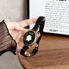 A hand holds a black resin beaded watch with a gold-toned casing and a white flower design on the face.