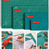 A set of green cutting mats with grid guides and various tools being used for crafting or cutting.