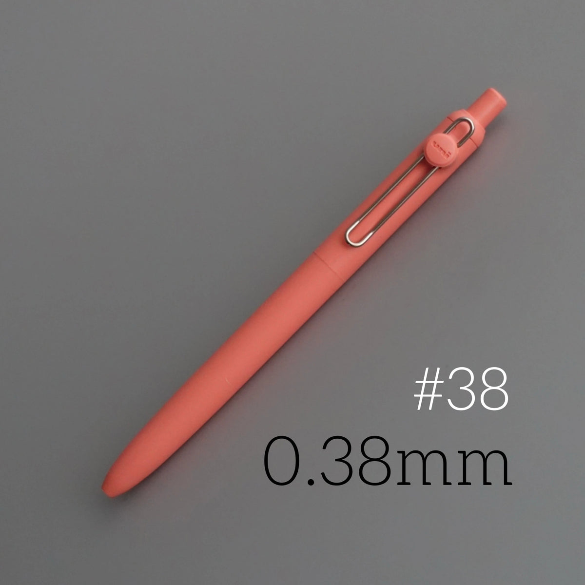 A close-up view of a rose-colored precision gel pen with a silver clip and a 0.38mm tip.