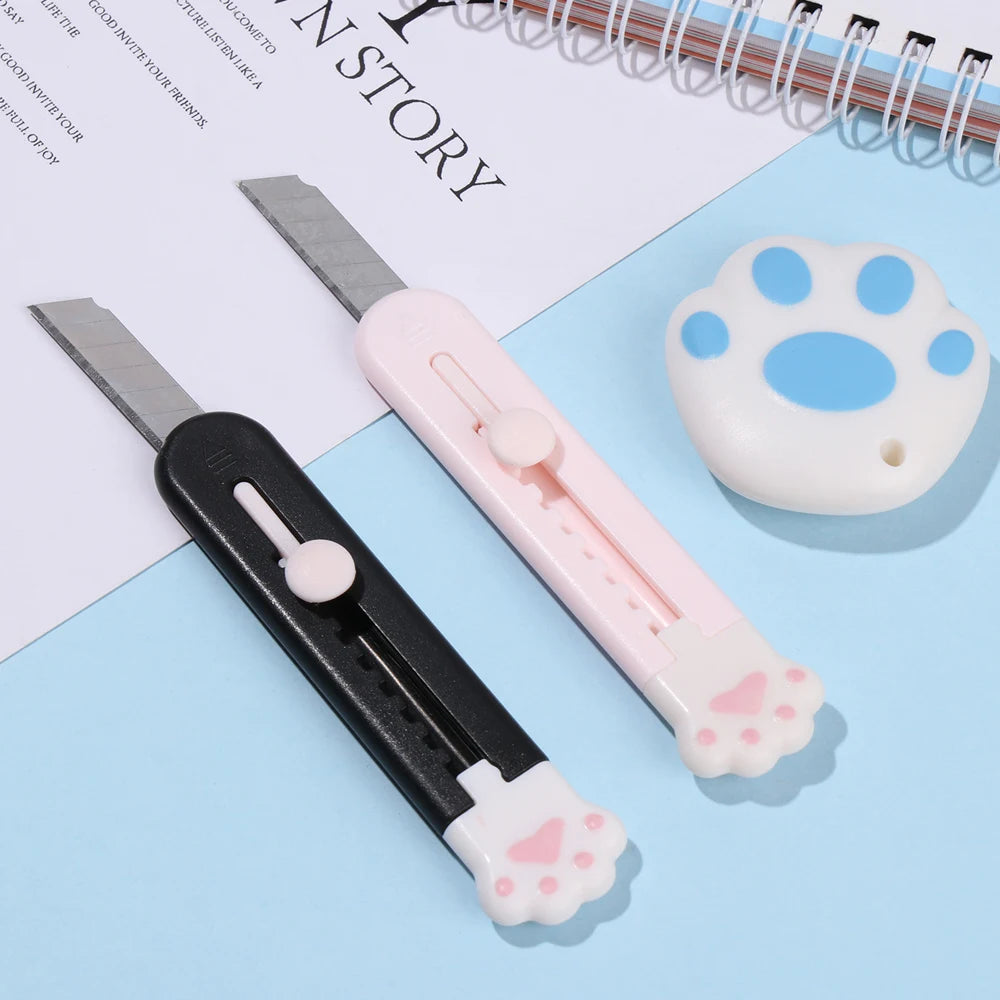 Pinkes und schwarzes, ausziehbares Multifunalklingen-Set mit Pfotenabdruck-Box cutter auf blauem Hintergrund