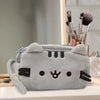 A gray plush cat pencil case with black accents resting on a white surface.