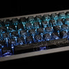 Close-up of blue side-lit PBT keycaps with intricate dragon designs on a keyboard layout.