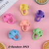 A collection of five colorful silicone pencil grips in yellow, pink, purple, orange, and green.