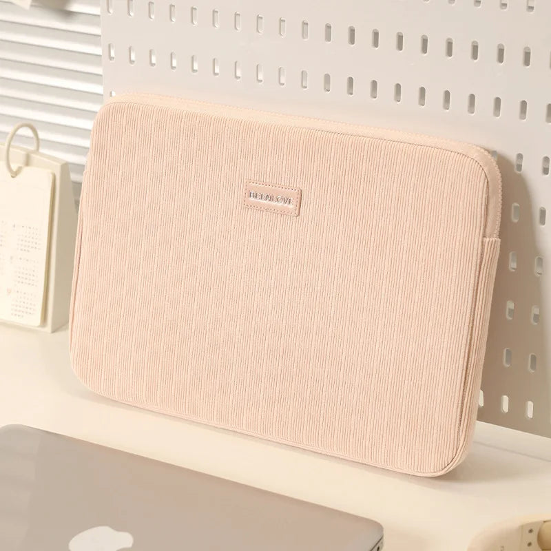 A beige fabric laptop sleeve is shown resting on a white surface against a light gray background.