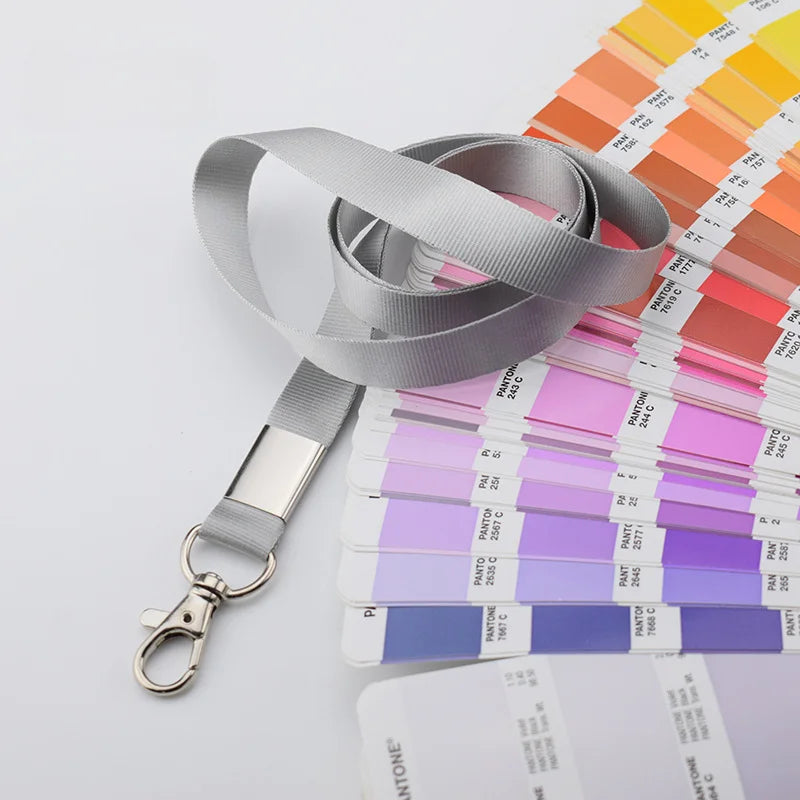Un rollo de soporte para credenciales duradero gris con tarjetas de plástico de varios colores y un clip de metal.