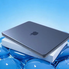 A silver Apple laptop is shown resting inside a white protective case, with blue liquid surrounding the object.