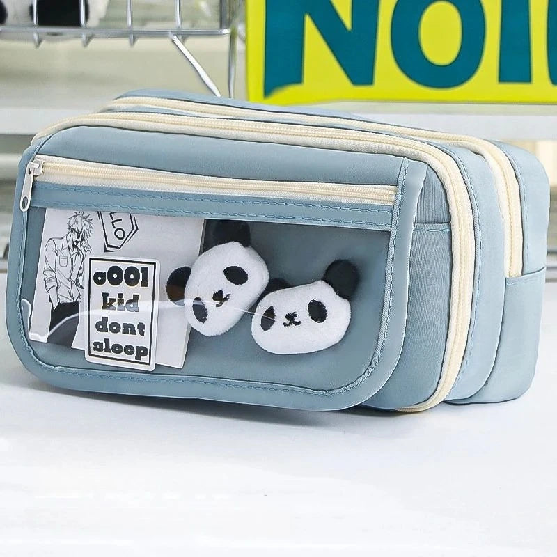 A light blue pencil case with a transparent flip pocket featuring a white panda charm.