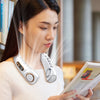 A woman is using a portable bladeless neck fan with cooling technology in a bright indoor setting.