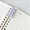 A close-up of a spiral notebook showing purple plastic binding rings and ruled paper.